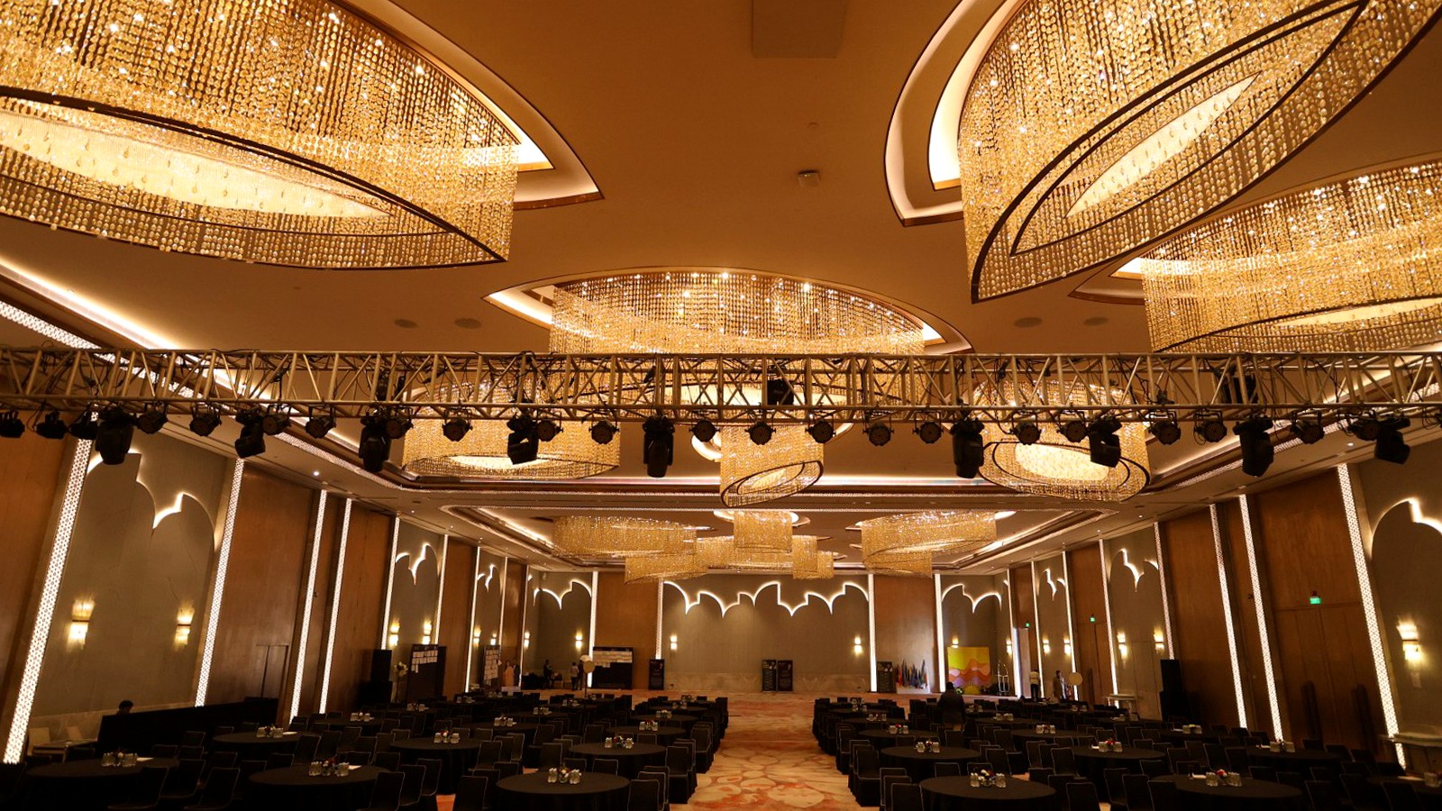 Conference hall arranged with black table settings beneath a lighting truss